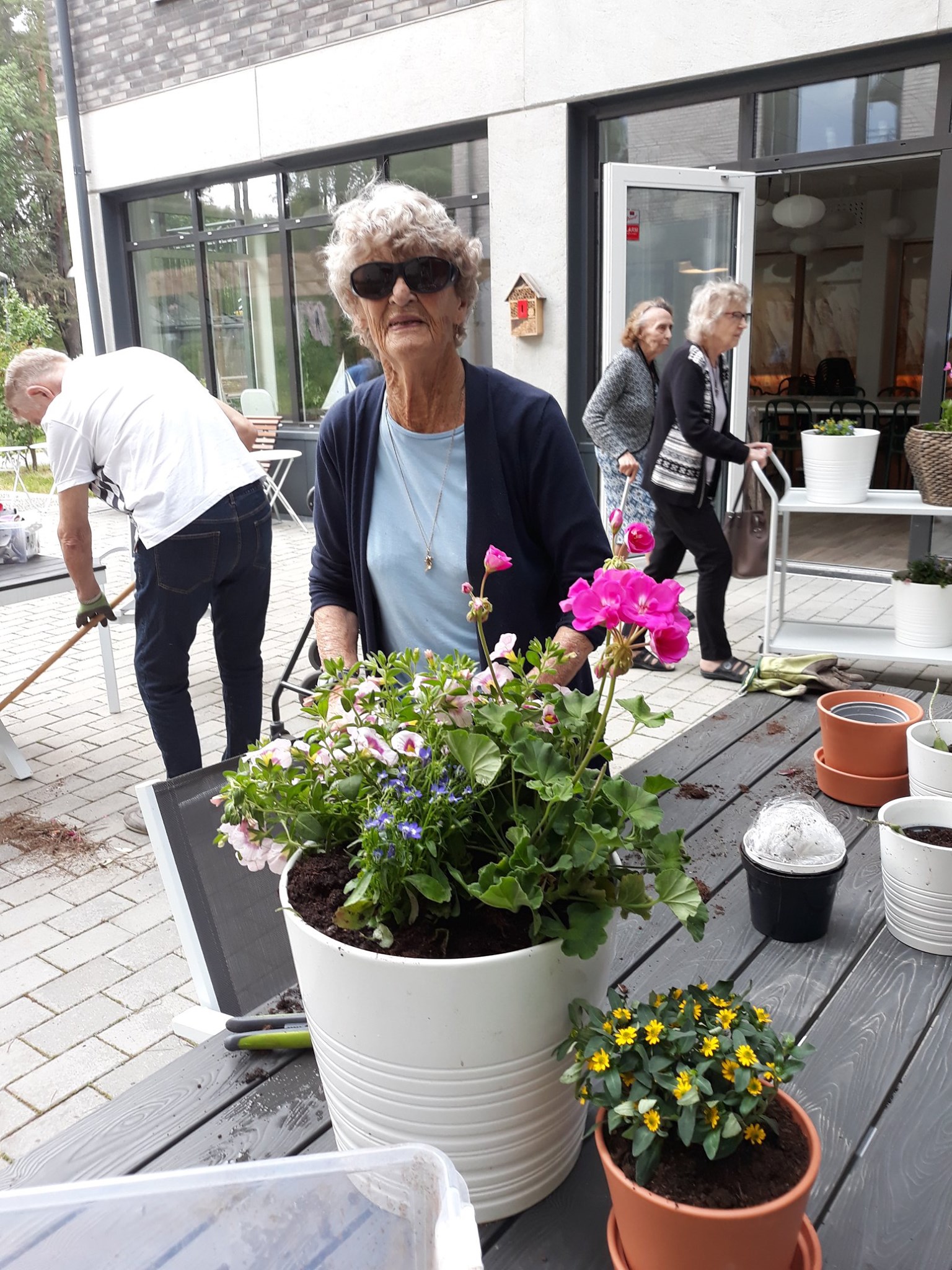 Britt planterar om blommor på bord