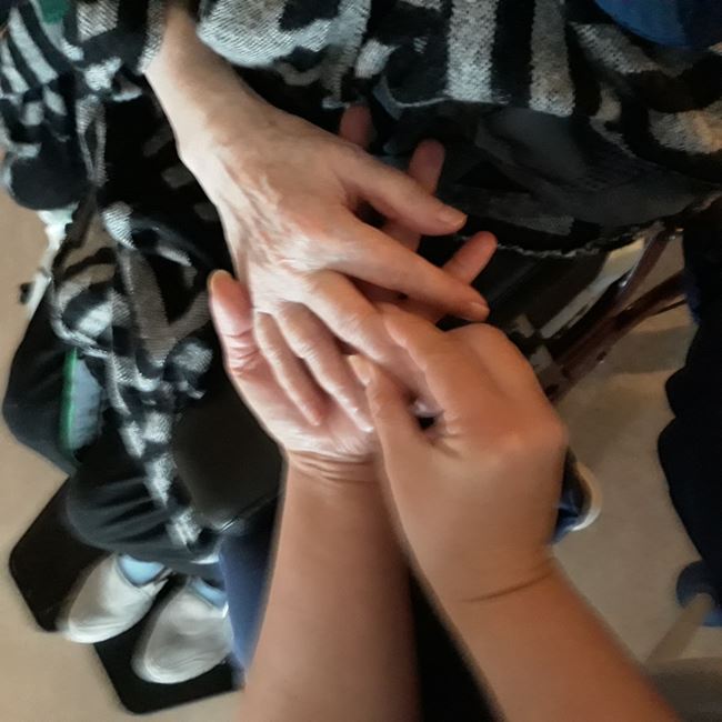 En vårdare håller en boende i handen