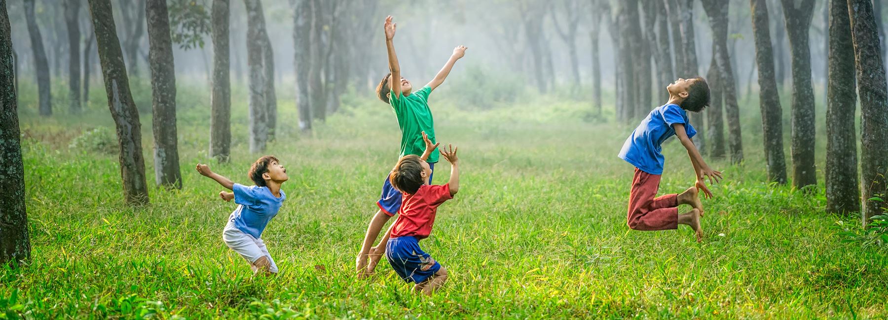 Barn som hoppar högt i gräset