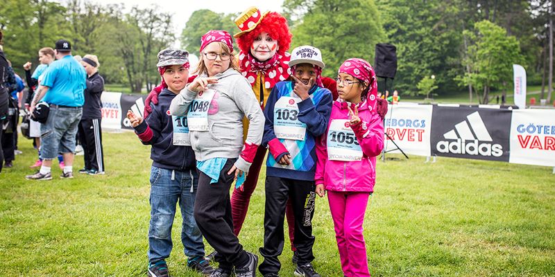 Fyra barn står och poserar med en person utklädd till clown. De har deltagit i Specialvarvet